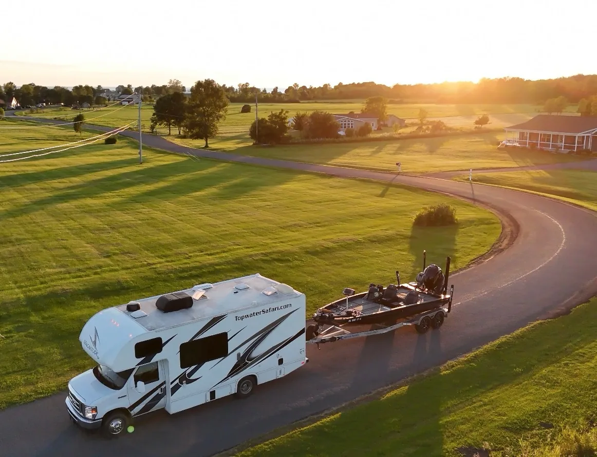 Captain Max's RV towing the bass boat down a country road at sunset