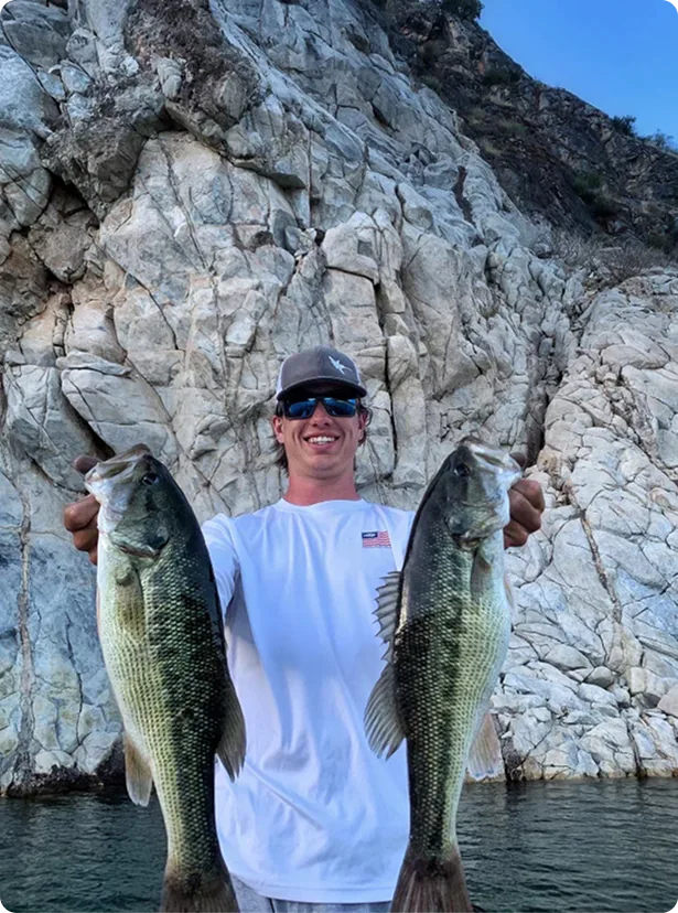 Captain Max on a fishing tour holding two bass